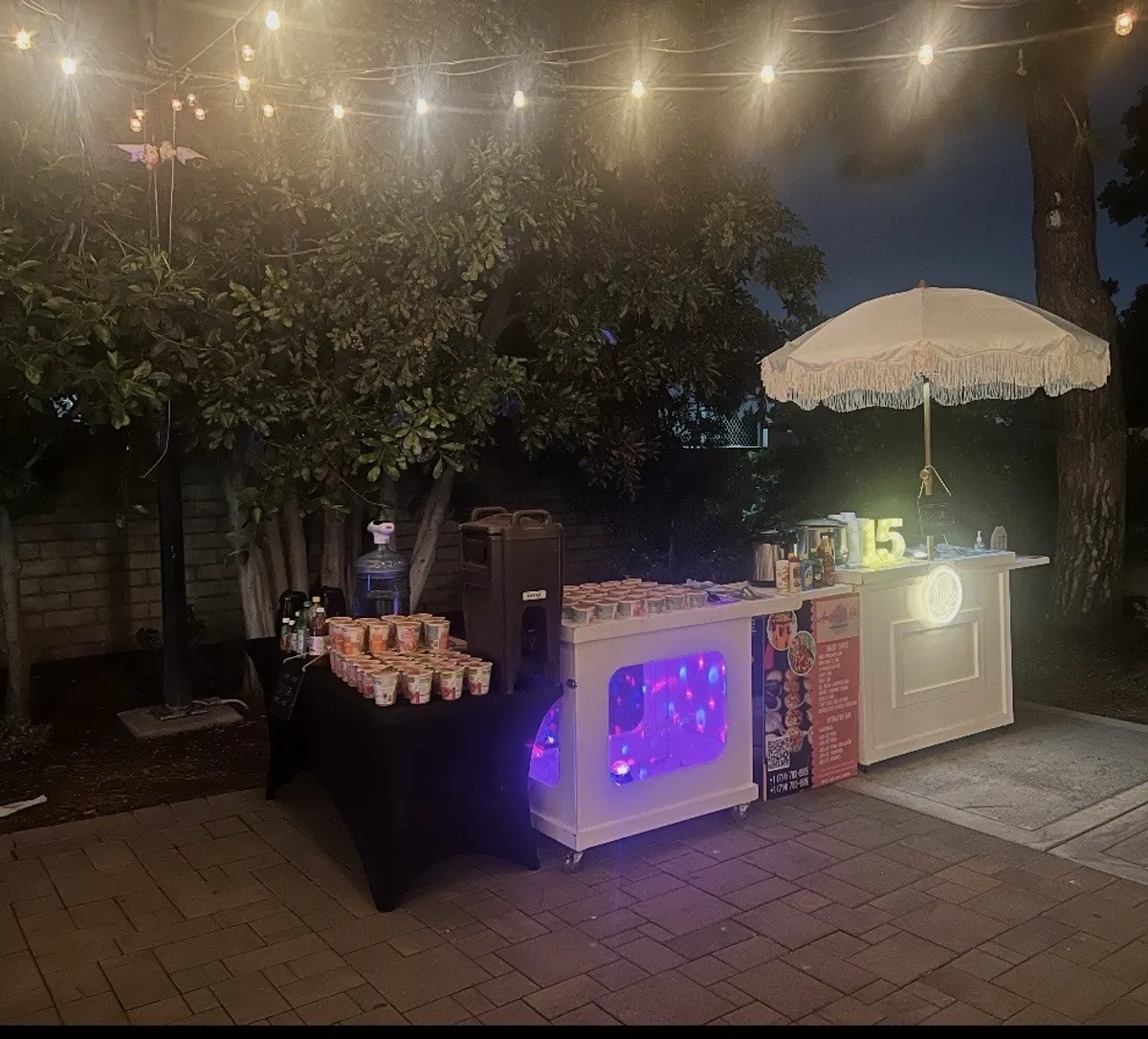 Amazing Little Bites snack cart set up outdoors at night with string lights for a 15th birthday celebration